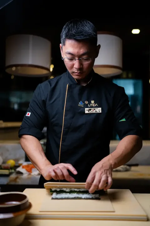 Chef William Utida preparando sushi no balcão do restaurante